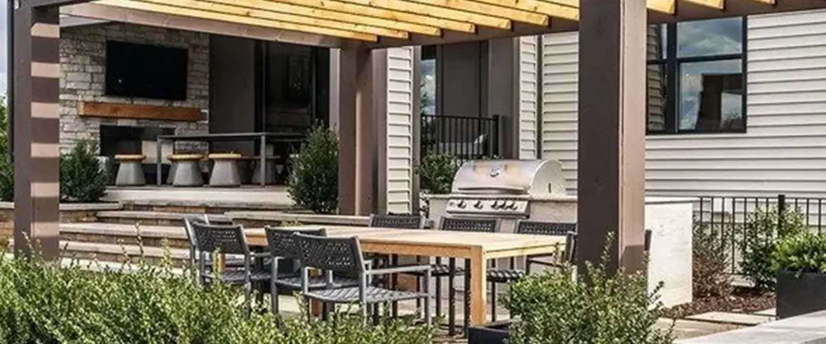 Pergola covering a patio with an outdoor kitchen and covered patio with television