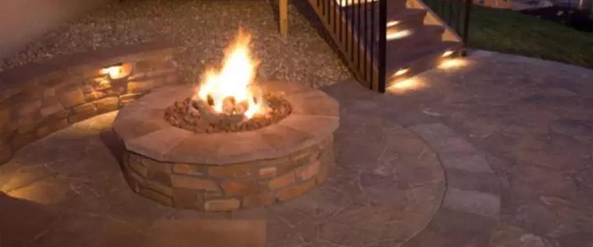 Patio with lit sitting wall around fire pit