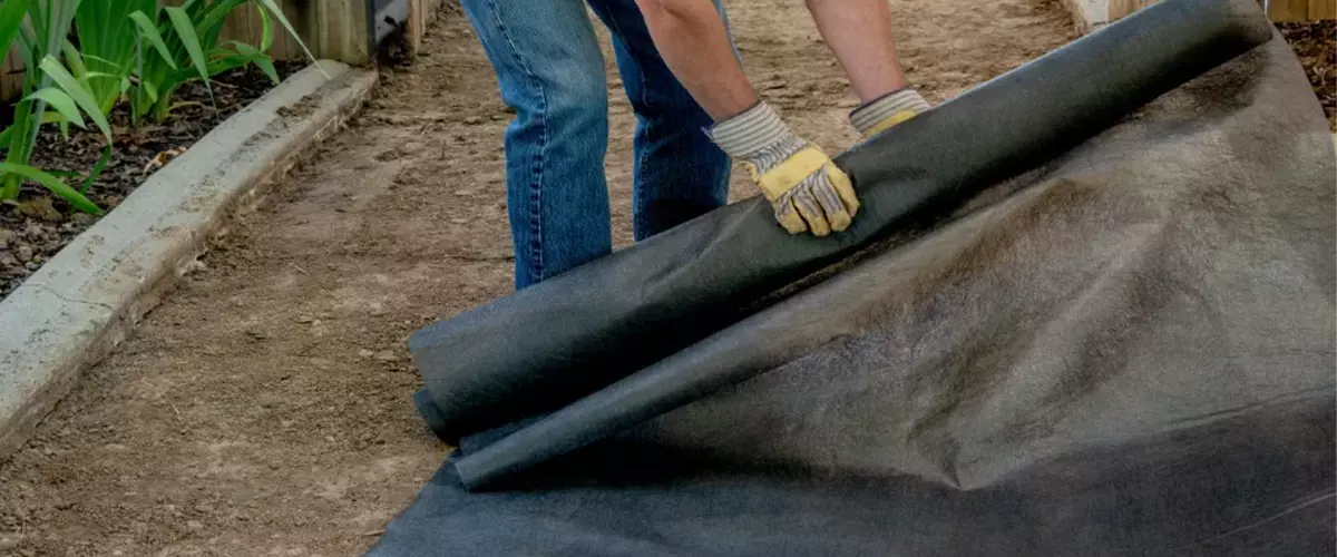 Laying down landscape fabric to act as a weed barrier