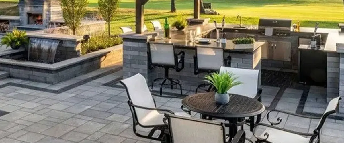 Patio with covered outdoor kitchen and dining area and fire place and water feature
