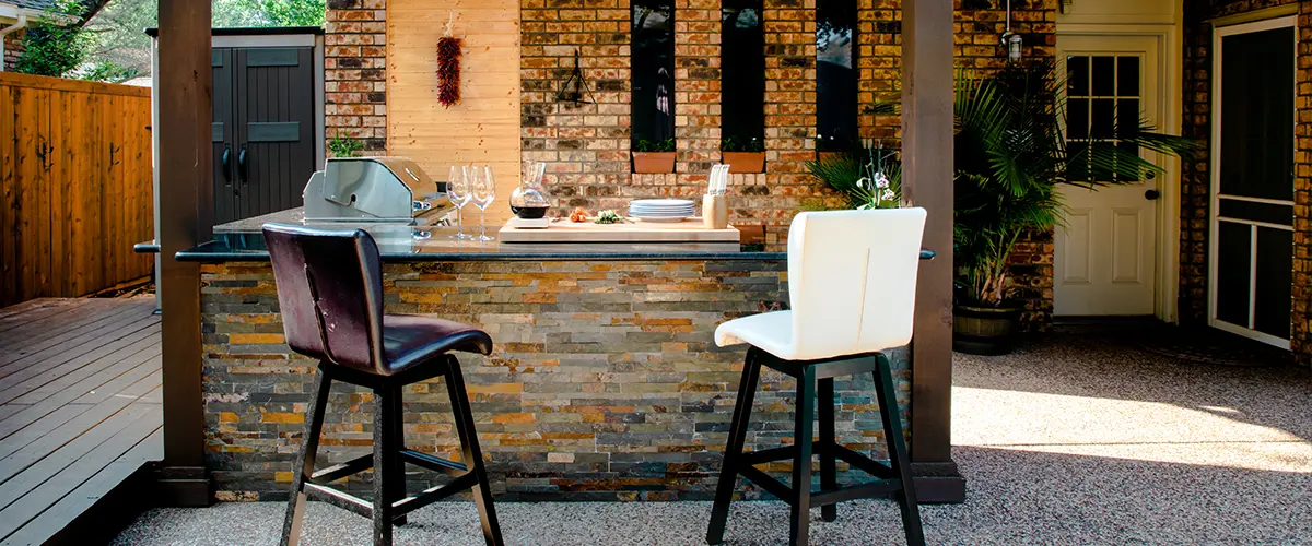 An outdoor kitchen with a bar and stools in Bryan, OH