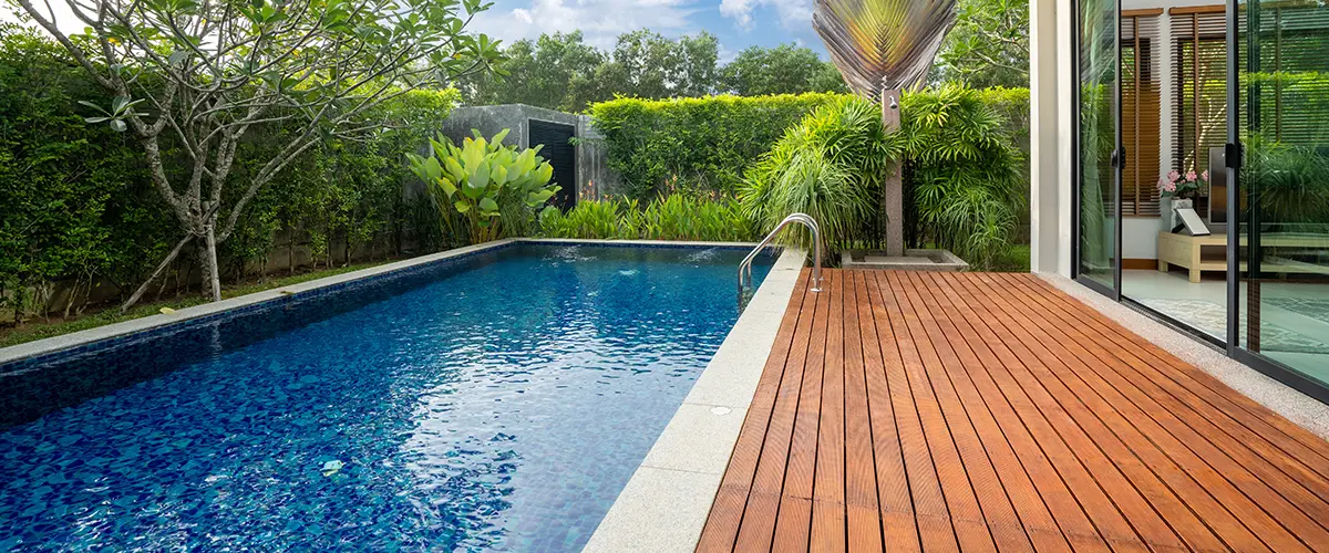 A composite deck with a pool and tall bushes