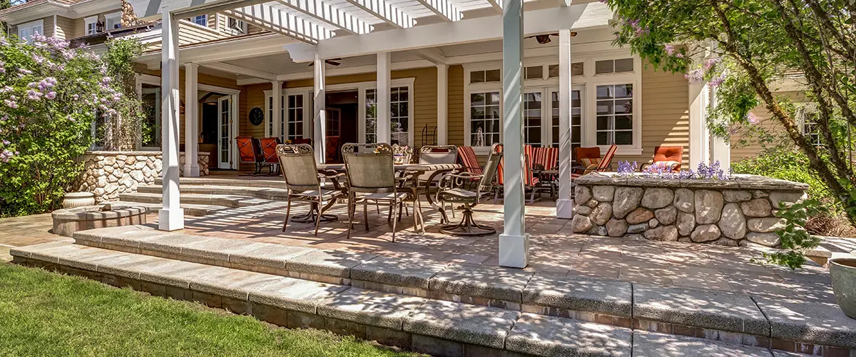A paver patio with a pergola, a fireplace, and outdoor furniture