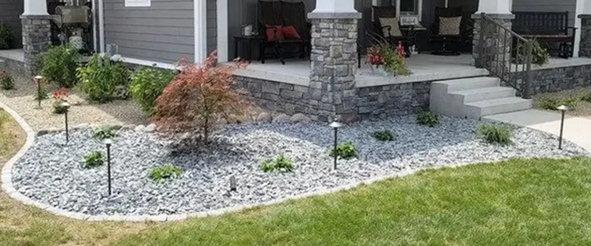 Closer up picture of gravel area with plants and garden lights running along the perimeter of a house