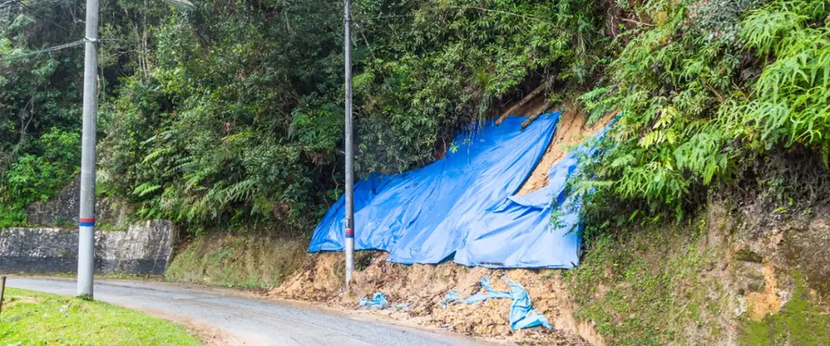An eroding hillside that is patially covered with a blue tarp.
