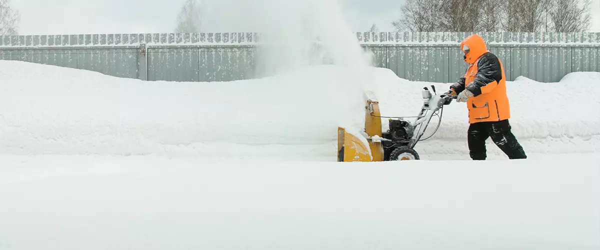 Man cleans snow with a snow thrower goes right to left