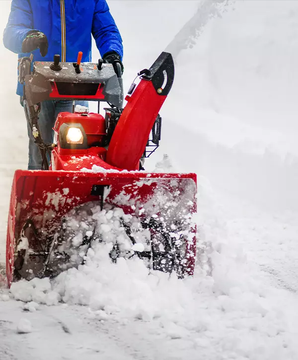 Man clearing or removing snow with a snowblower on a snowy road detail The Best Snow Removal In Bryan, OH