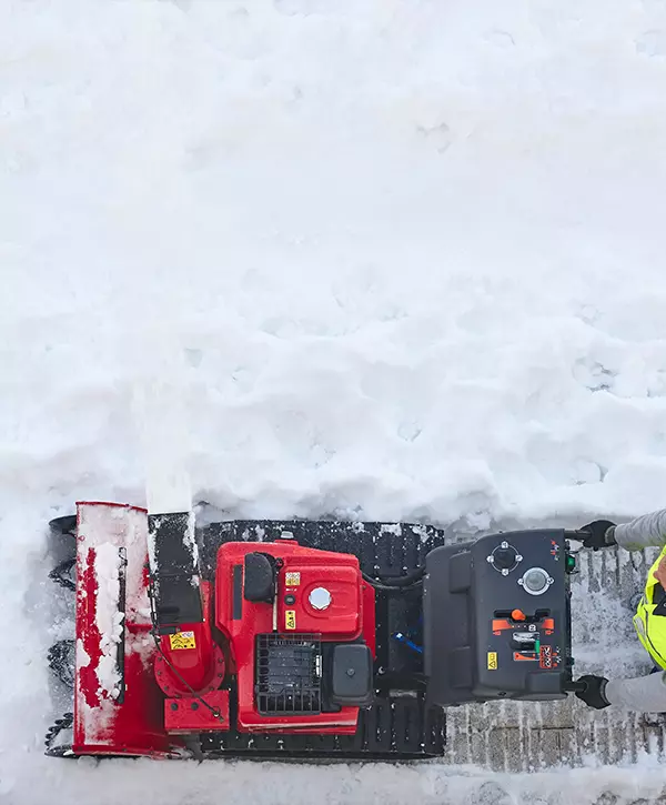 Worker cleaning snow on the sidewalk with a snowblower in Defiance