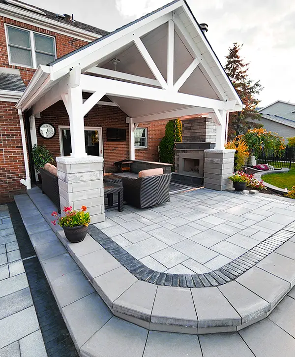 Elegant patio with a covered seating area, outdoor fireplace, and neatly arranged potted plants