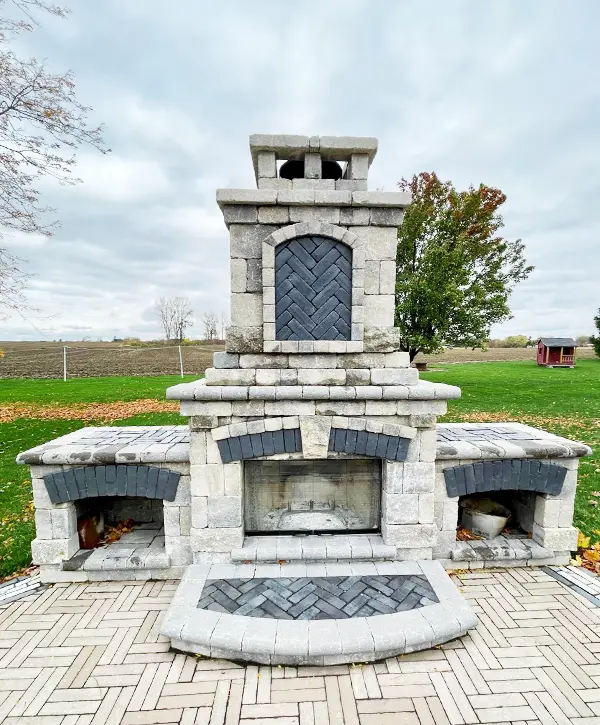 Large outdoor stone fireplace with herringbone pattern detailing on a patio.