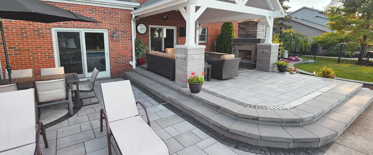 Large backyard patio featuring a covered seating area, dining table with umbrella, and adjacent lounge chairs