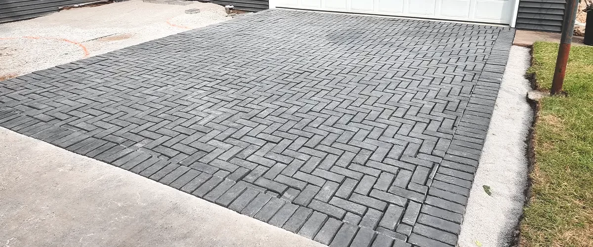 Newly paved brick driveway in a herringbone pattern leading to a two-car garage with a red side door